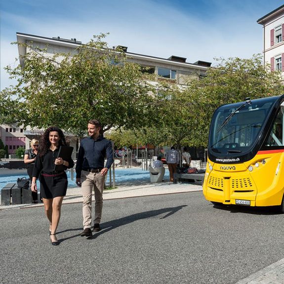 Une navette autonome et deux piétons dans les rues de Sion